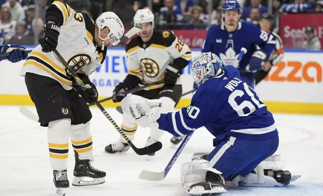 Toronto Maple Leafs goalie Joseph Woll (60) makes a save as Boston Bruins left wing Brad Marchand (63) digs in during the first period of an NHL hockey game in Toronto, Saturday, Jan. 4, 2025. (Frank Gunn/The Canadian Press via AP)