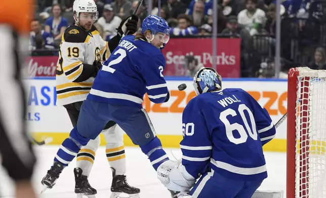 Toronto Maple Leafs defenseman Simon Benoit (2) watches the puck pass him on a shot towards teammate Joseph Woll (60) as Boston Bruins center John Beecher (19) looks on during the first period of an NHL hockey game in Toronto, Saturday, Jan. 4, 2025. (Frank Gunn/The Canadian Press via AP)