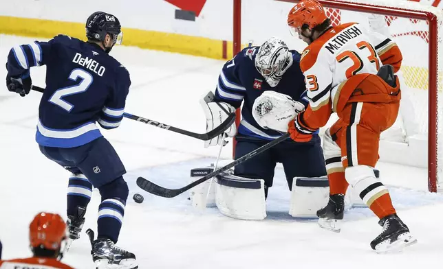 Winnipeg Jets goaltender Connor Hellebuyck (37) saves the shot from Anaheim Ducks' Mason McTavish (23) during the first period of an NHL game in Winnipeg, Manitoba, Thursday, Jan. 2, 2025. (John Woods/The Canadian Press via AP)