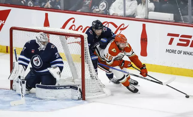 Winnipeg Jets' Vladislav Namestnikov (7) chases down Anaheim Ducks' Jansen Harkins (38) around the net of goaltender Connor Hellebuyck (37) during the first period of an NHL game in Winnipeg, Manitoba, Thursday, Jan. 2, 2025. (John Woods/The Canadian Press via AP)