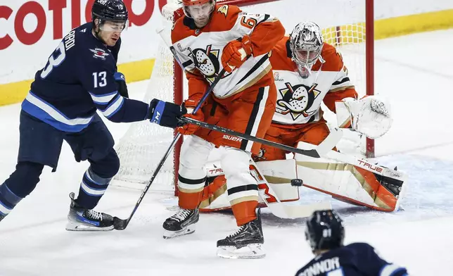 Anaheim Ducks goaltender John Gibson (36) saves the shot from Winnipeg Jets' Kyle Connor (81) as Anaheim's Jacob Trouba (65) and Winnipeg's Gabriel Vilardi (13) jostle at the net during the first period of an NHL game in Winnipeg, Manitoba, Thursday, Jan. 2, 2025. (John Woods/The Canadian Press via AP)