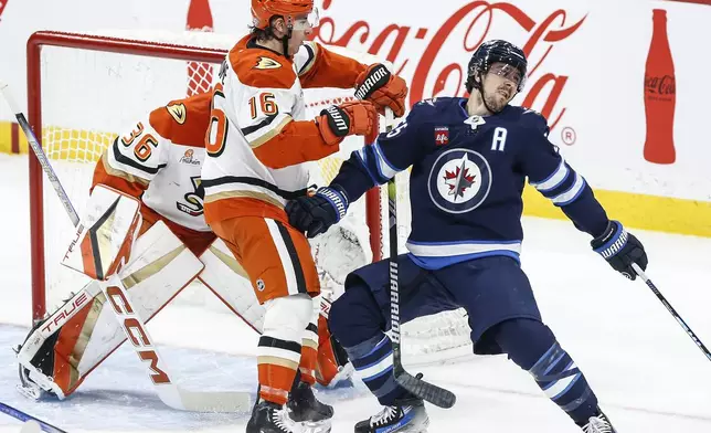 Winnipeg Jets' Mark Scheifele (55) gets tripped by Anaheim Ducks' Ryan Strome (16) in front of goaltender John Gibson (36) during the second period of an NHL game in Winnipeg, Manitoba, Thursday, Jan. 2, 2025. Strome was assessed a two minute minor for tripping. (John Woods/The Canadian Press via AP)