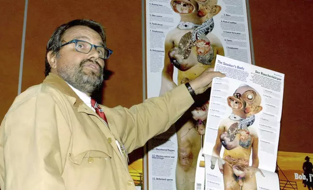 EDS NOTE: NUDITY - File - Italian photographer Oliviero Toscani holds a poster showing a "Smoker's Body" during a press conference on tobacco advertising, in Geneva, Switzerland, Thursday, March 21, 2002. (AP Photo/ Donald Stampfli, File)