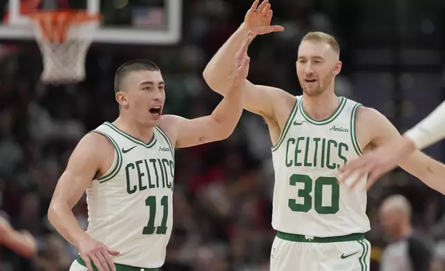 Boston Celtics' Payton Pritchard (11) celebrates with Sam Hauser (30) after making a 3-pointer against the Houston Rockets during the second half of an NBA basketball game Friday, Jan. 3, 2025, in Houston. The Celtics won 109-86. (AP Photo/David J. Phillip)