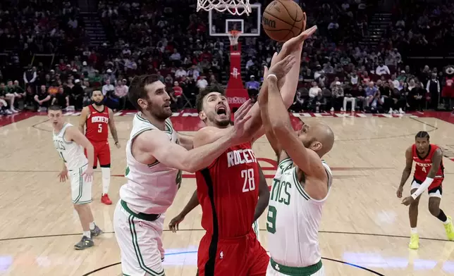 Houston Rockets' Alperen Sengun (28) goes up for a shot as Boston Celtics' Derrick White (9) and Luke Kornet defend during the first half of an NBA basketball game Friday, Jan. 3, 2025, in Houston. (AP Photo/David J. Phillip)