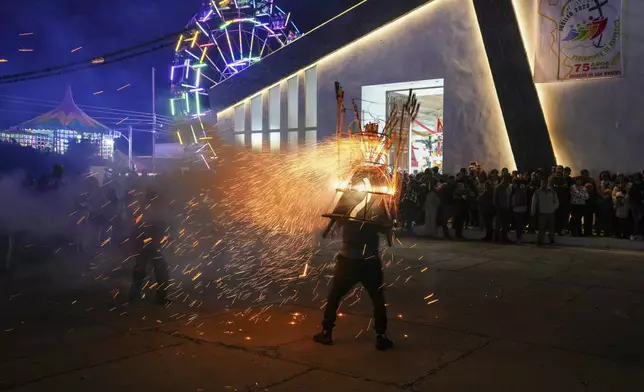 A man wears a "torito" fireworks display during the celebration of the Black Christ of Esquipulas the night before its feast day in Esquipulas Palo Gordo, in Guatemala's San Marcos department, Tuesday, Jan. 14, 2025. (AP Photo/Moises Castillo)