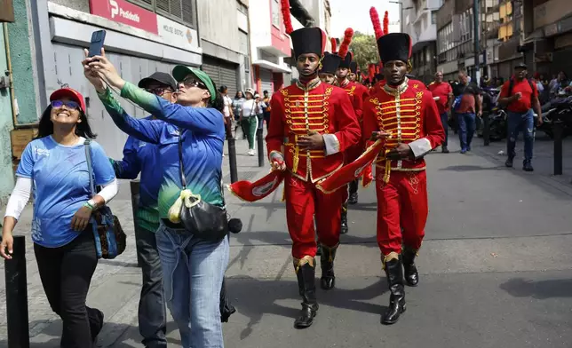 Government supporters take a selfie with honor guards behind them marching after the swearing-in ceremony for Venezuelan President Nicolas Maduro for a third term in Caracas, Venezuela, Jan. 10, 2025. (AP Photo/Cristian Hernandez)