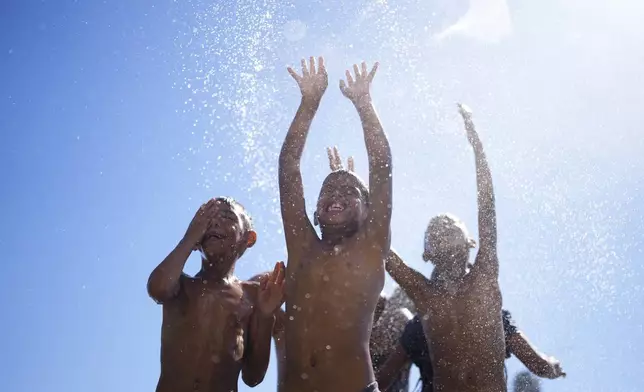 Children play in the spray of a water hose during summer in Buenos Aires, Argentina, Jan. 13, 2025. (AP Photo/Natacha Pisarenko)