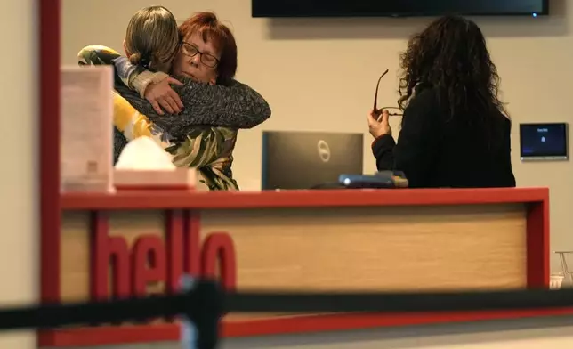 Women embrace in the reception area of The Skating Club of Boston, where six athletes, coaches and family associated with the club are believed to have perished in the collision of a passenger aircraft and military helicopter in Washington, Thursday, Jan. 30, 2025, in Norwood, Mass. (AP Photo/Robert F. Bukaty)