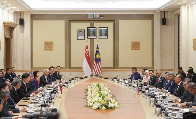 Singapore Prime Minister Lawrence Wong, center left, with his delegation members meets with Malaysian Prime Minister Anwar Ibrahim, third right, at the prime minister's office in Putajaya, Malaysia, Tuesday, Jan. 7, 2025. (AP Photo/Vincent Thian, Pool)