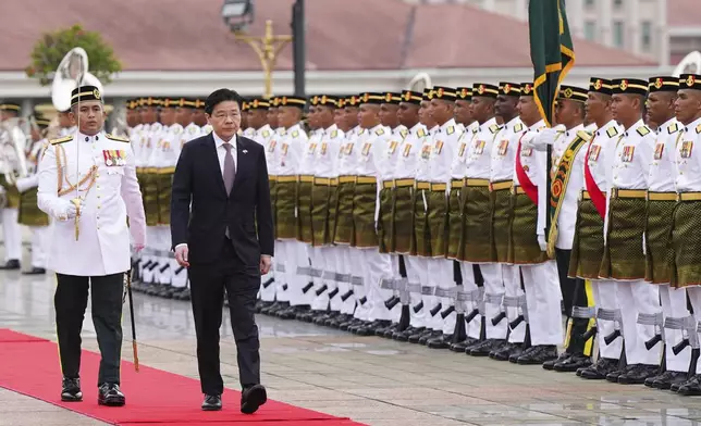 Singapore Prime Minister Lawrence Wong, right, inspects honor guards during a welcoming ceremony prior to his meeting with Malaysian Prime Minister Anwar Ibrahim, unseen, in Putrajaya, Malaysia, Tuesday, Jan. 7, 2025. (AP Photo/Vincent Thian, Pool)