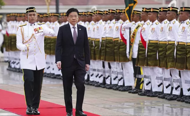 Singapore Prime Minister Lawrence Wong, right, inspects honor guards during a welcoming ceremony prior to his meeting with Malaysian Prime Minister Anwar Ibrahim, unseen, in Putrajaya, Malaysia, Tuesday, Jan. 7, 2025. (AP Photo/Vincent Thian, Pool)