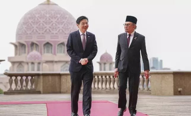 Singapore Prime Minister Lawrence Wong, left, walks with Malaysian Prime Minister Anwar Ibrahim with the background of Putra Mosque during a welcoming ceremony prior to their meeting in Putrajaya, Malaysia, Tuesday, Jan. 7, 2025. (AP Photo/Vincent Thian, Pool)