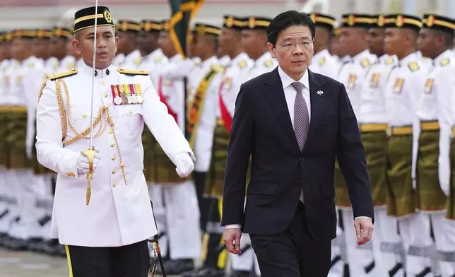 Singapore Prime Minister Lawrence Wong, right, inspects honor guards during a welcoming ceremony prior to his meeting with Malaysian Prime Minister Anwar Ibrahim, unseen, in Putrajaya, Malaysia, Tuesday, Jan. 7, 2025. (AP Photo/Vincent Thian, Pool)