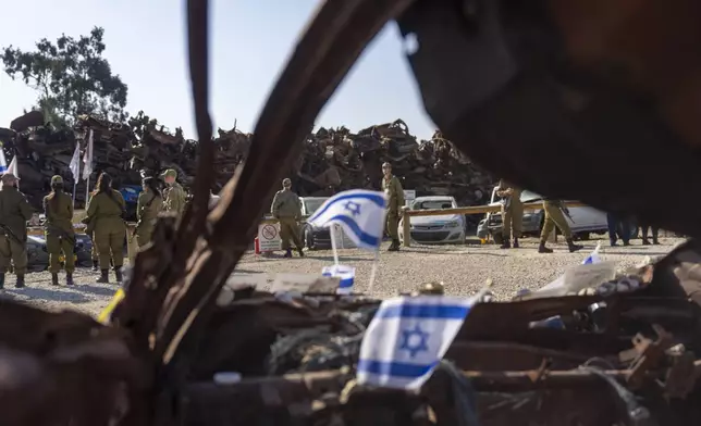 Israeli soldiers look at charred vehicles burned in the Oct. 7 , 2023, cross-border attacks by Hamas militants outside the town of Netivot, southern Israel, Monday, Jan. 13, 2025. (AP Photo/Ariel Schalit)