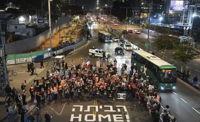 Demonstrators hold torches during a protest calling for the immediate release of the hostages held in the Gaza Strip by the Hamas militant group in Tel Aviv, Israel, on Monday, Jan. 13, 2025. (AP Photo/Ohad Zwigenberg)