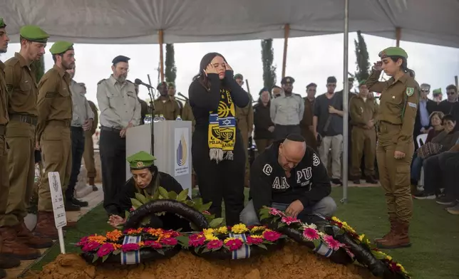 Gali and Nir, the parents of the Israeli soldier Sergeant Yahav Maayan who was killed in combat in the Gaza Strip, react next to his grave during his funeral at a military cemetery in Modiin, Israel, Sunday, Jan. 12, 2025. (AP Photo/Ohad Zwigenberg)