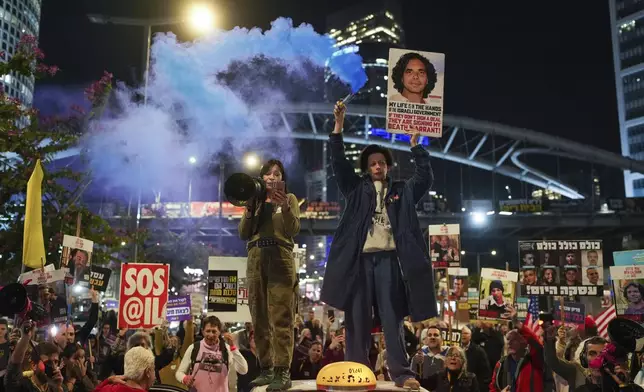 Demonstrators hold signs and flares during a protest calling for the immediate release of the hostages held in the Gaza Strip by the Hamas militant group in Tel Aviv, Israel, on Monday, Jan. 13, 2025. (AP Photo/Ohad Zwigenberg)