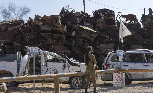 An Israeli soldier looks at charred vehicles burned in the Oct. 7 , 2023, cross-border attacks by Hamas militants outside the town of Netivot, southern Israel, Monday, Jan. 13, 2025. (AP Photo/Ariel Schalit)