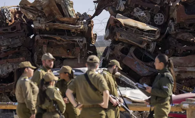 Israeli soldiers look at charred vehicles burned in the Oct. 7 , 2023, cross-border attacks by Hamas militants outside the town of Netivot, southern Israel, Monday, Jan. 13, 2025. (AP Photo/Ariel Schalit)