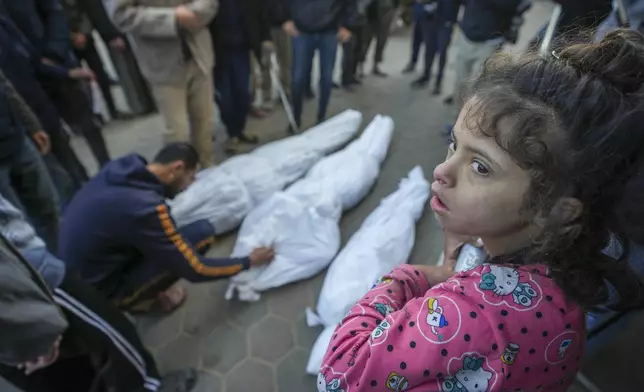 A girl watches as Mohammad Eid mourns his cousin Dima, along with her uncle and grandfather, who were killed in an Israeli airstrike on Saturday, during their funeral in Deir al-Balah, central Gaza Strip, Sunday, Jan. 12, 2025. (AP Photo/Abdel Kareem Hana)