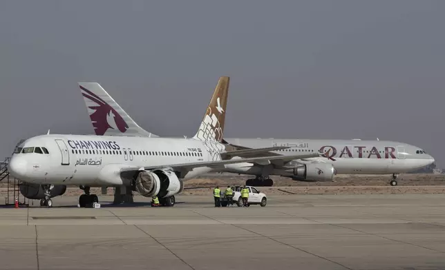 Qatar Airways plane, background, a first international commercial flight since the fall of former Syrian President Bashar Assad, lands at Damascus international airport arriving from Qatar, in Damascus, Syria, Tuesday, Jan. 7, 2025. (AP Photo/Omar Sanadiki)