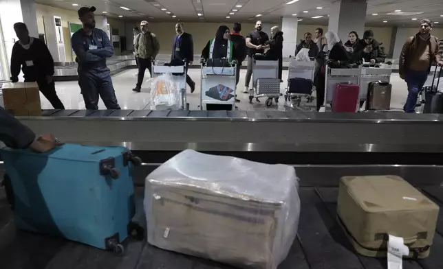 Passengers who arrived at a first international commercial flight since the fall of former Syrian President Bashar Assad, wait to receive their luggages at the arrival terminal of Damascus international airport, in Damascus, Syria, Tuesday, Jan. 7, 2025. (AP Photo/Omar Sanadiki)