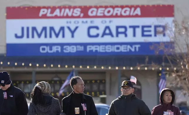 People wait for a funeral procession for former President Jimmy Carter to move through downtown Plains, Ga., Saturday, Jan. 4, 2025. (AP Photo/Mike Stewart)