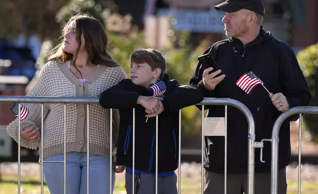 People watch as a hearse carrying the flag-draped casket of former President Jimmy Carter moves through downtown Plains, Ga., Saturday, Jan. 4, 2025. (AP Photo/Mike Stewart)