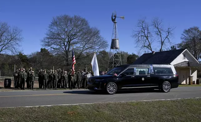 NPS employees, based out of Sumter County, Ga., salute the hearse carrying the flag-draped casket of former President Jimmy Carter as the motorcade stops in front of the Boyhood Farm, where President Carter grew up, Saturday, Jan. 4, 2025, in Plains, Ga. (Hyosub Shin/Atlanta Journal-Constitution via AP, Pool)