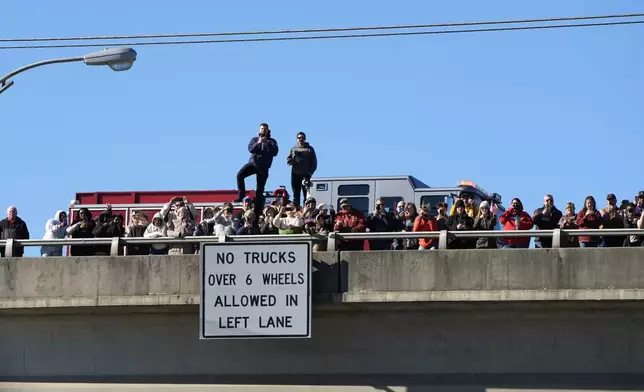 People watch from an overpass as the hearse containing the casket of former President Jimmy Carter drives on I-75 through Forsyth, Ga., Saturday, Jan. 4, 2025, en route to Atlanta. Carter died Dec. 29 at the age of 100. (AP Photo/Alex Brandon, Pool)