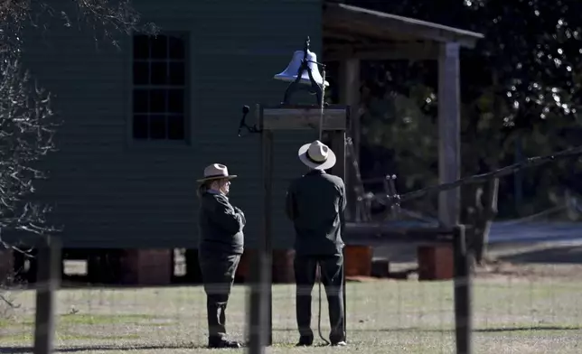 Karen Barry, left, and Randy Dillard, the longest serving NPS Plains staffers, ring the farm bell 39 times as the motorcade with the flag-draped hearse of former President Jimmy Carter stops in front of the Boyhood Farm, where Carter grew up, Saturday, Jan. 4, 2025, Plains, Ga. (Hyosub Shin/Atlanta Journal-Constitution via AP, Pool)