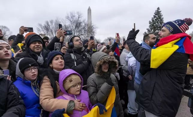 A man wearing a hat for President-elect Donald Trump's inauguration records supporters of Edmundo Gonzalez, who represented Venezuela's main opposition coalition in the July presidential election, as they sing outside of the Organization of American States, Monday, Jan. 6, 2025, in Washington. (AP Photo/Jacquelyn Martin)