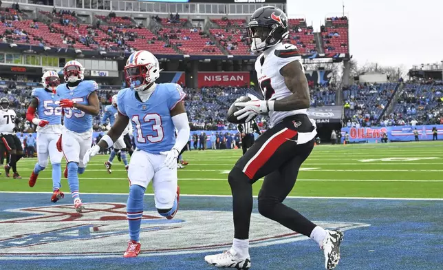 Houston Texans wide receiver Nico Collins (12) catches a pass for a touchdown as Tennessee Titans cornerback Chidobe Awuzie (13) defends during the first half of an NFL football game Sunday, Jan. 5, 2025, in Nashville, Tenn. (AP Photo/John Amis)