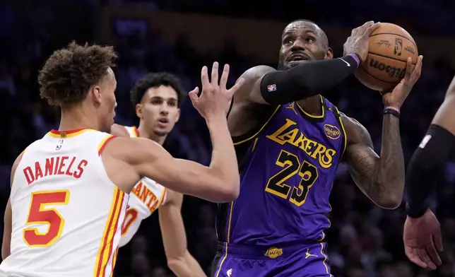 Los Angeles Lakers forward LeBron James, right, shoots as Atlanta Hawks guard Dyson Daniels defends during the first half of an NBA basketball game, Friday, Jan. 3, 2025, in Los Angeles. (AP Photo/Mark J. Terrill)