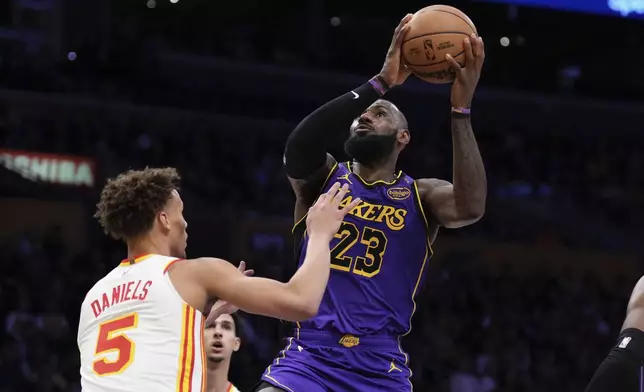 Los Angeles Lakers forward LeBron James, right, shoots as Atlanta Hawks guard Dyson Daniels defends during the first half of an NBA basketball game, Friday, Jan. 3, 2025, in Los Angeles. (AP Photo/Mark J. Terrill)