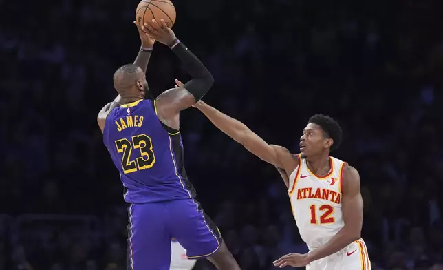 Los Angeles Lakers forward LeBron James, left, shoots as Atlanta Hawks forward De'Andre Hunter defends during the second half of an NBA basketball game, Friday, Jan. 3, 2025, in Los Angeles. (AP Photo/Mark J. Terrill)