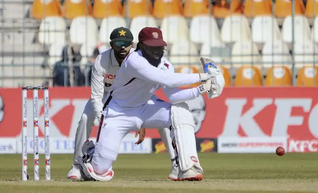 West Indies Jomel Warrican, front, plays a shot as Pakistan's Babar Azam watches during the day-one of the second cricket test match between Pakistan and West Indies, in Multan, Pakistan, Saturday, Jan. 25, 2025. (AP Photo/Asim Tanveer)
