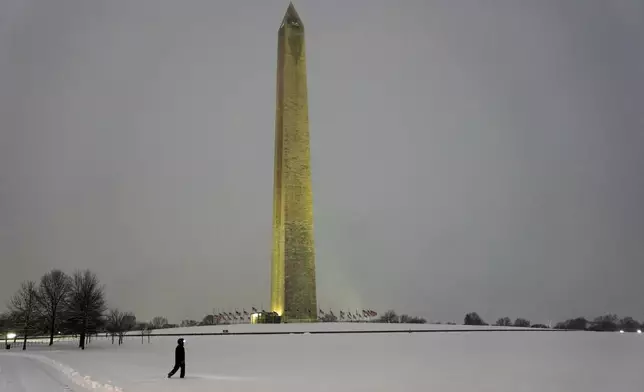 A person walks near the Washington Monument during a winter snow storm in Washington, Monday, Jan. 6, 2025. (AP Photo/Matt Rourke)