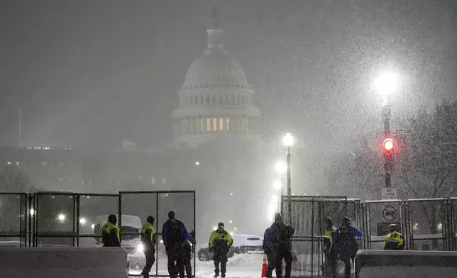 Law enforcement officers stand guard at the Capitol as snow falls ahead of a joint session of Congress to certify the votes from the Electoral College in the presidential election, in Washington, Monday, Jan. 6, 2025. (AP Photo/Matt Rourke)