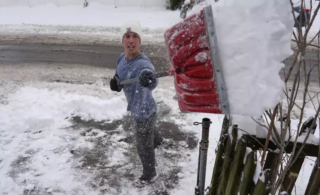 Ben Sisarsky pitches snow over a fence as he clears his girlfriend's parking spot with a borrowed snow shovel in Cincinnati, Tuesday, Jan. 7, 2025. (AP Photo/Carolyn Kaster)