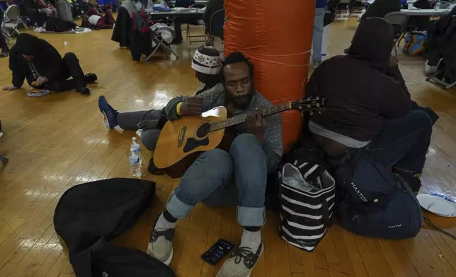 Tirrdell Byrd plays guitar while sheltering from the cold inside a recreation center, Monday, Jan. 6, 2025, in Cincinnati. (AP Photo/Joshua A. Bickel)