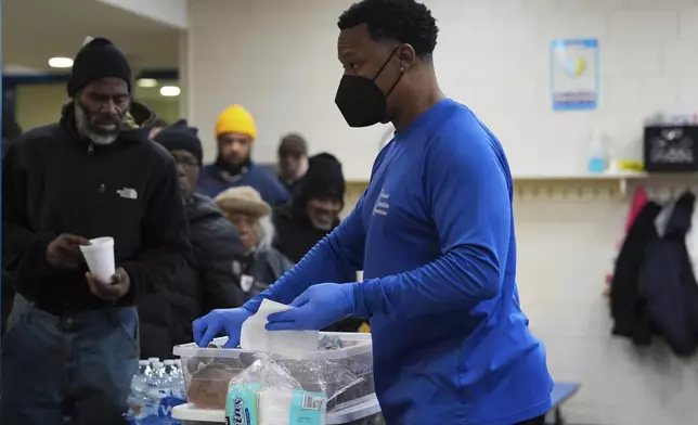 Idris Mills, right, hands out food to patrons inside a daytime warming shelter, Tuesday, Jan. 7, 2025, in Cincinnati. (AP Photo/Joshua A. Bickel)