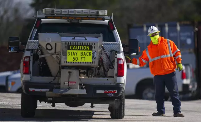 A worker is bundled up in near-freezing temperatures as he loads into a salt spreading truck at the Texas Department of Transportation Dallas Southwest lot as crews prepare the roads ahead of a winter storm expected to hit the North Texas region, Tuesday, Jan. 7, 2025, in Cedar Hill, Texas. (AP Photo/Julio Cortez)