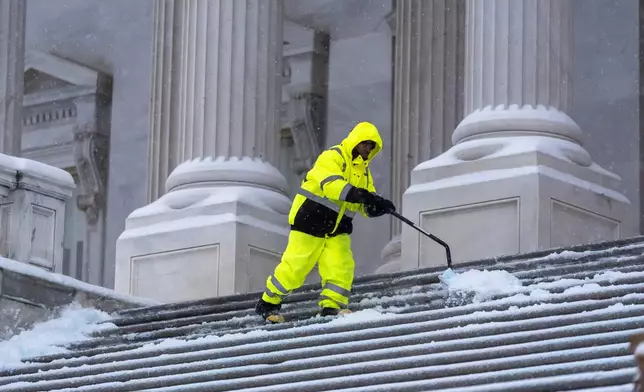 A workman clears steps at the Capitol as snow falls ahead of a joint session of Congress to certify the votes from the Electoral College in the presidential election, in Washington, Monday, Jan. 6, 2025. (AP Photo/J. Scott Applewhite)