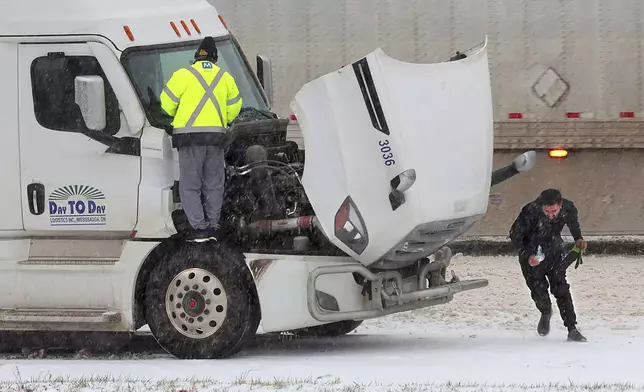 Truckers fight the weather as they stop on Interstate 44 in Fenton, Mo. to change wiper blades as sleet falls on Sunday, Jan. 5, 2025. (Cohen/St. Louis Post-Dispatch via AP)