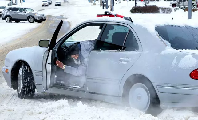 St. Ann resident Troupe El checks for traction on Monday, Jan. 6, 2025, after getting his vehicle stuck trying to enter St. Charles Rock Road from the Crossings at Northwest in St. Ann, Mo. (Christian Gooden/St. Louis Post-Dispatch via AP)