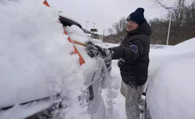 Cary Fallath, the BMW Store lot technician, clears snow from new cars in Silverton, Ohio, Tuesday, Jan. 7, 2025. (AP Photo/Carolyn Kaster)