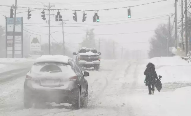 Heavy snow falls as a person walks along U.S. Route 42 in Florence, Ky., Monday, Jan. 6, 2025. (AP Photo/Carolyn Kaster)