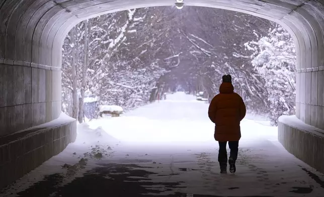 A pedestrian makes their way though a tunnel along the snow-covered Monon Trail in Carmel, Ind., Monday, Jan. 6, 2025. (AP Photo/Michael Conroy)